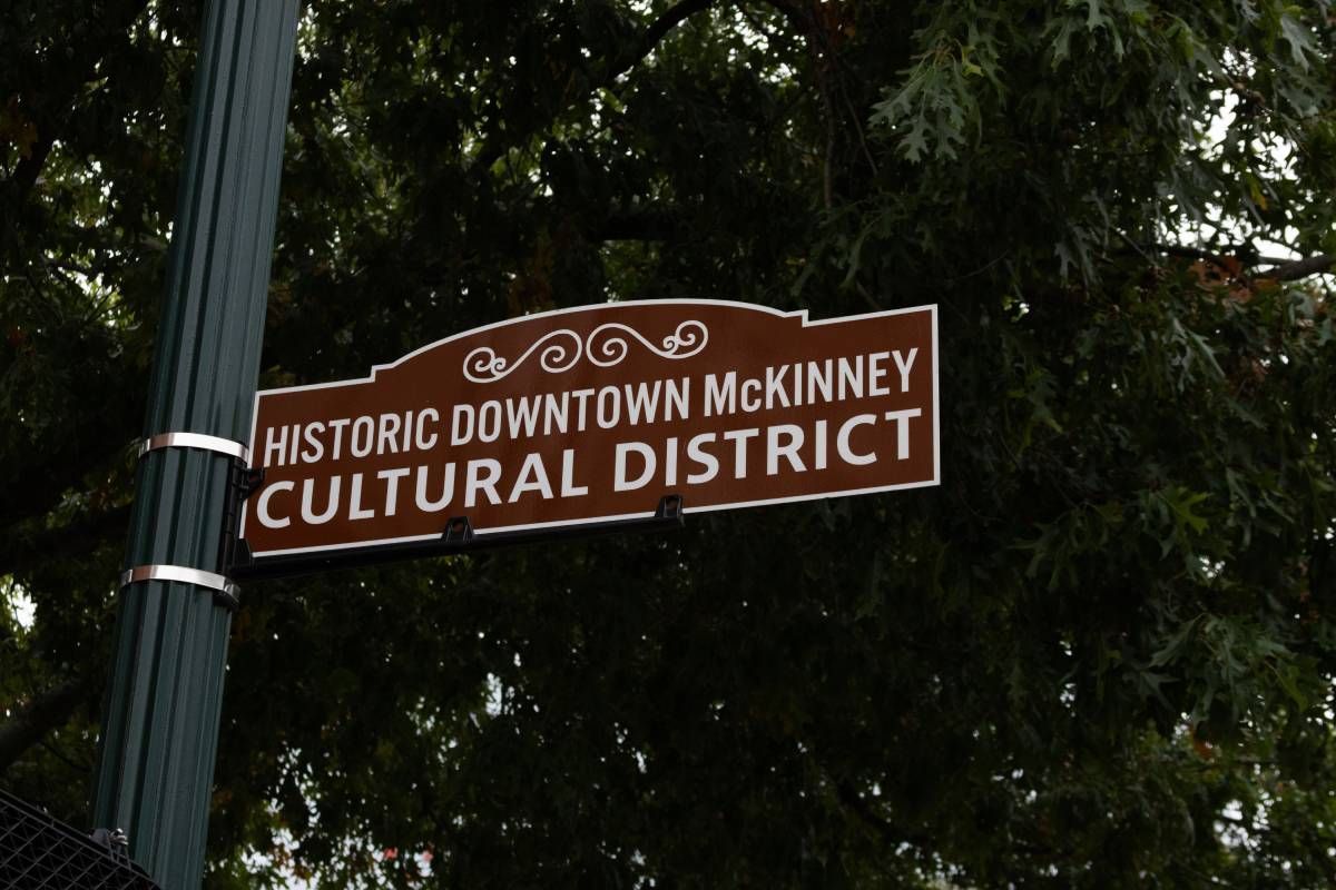 Image of a street sign Historic Downtown McKinney Cultural District, with a large tree behind it