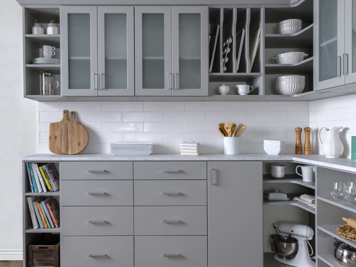 A kitchen with gray cabinets , drawers , shelves and a mixer.