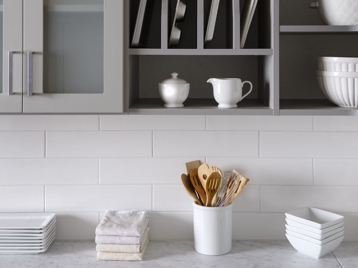 A kitchen counter with plates , bowls , and utensils on it.