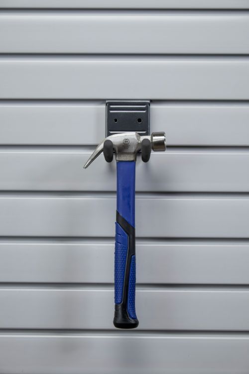 A hammer is hanging on a hook on a wall.