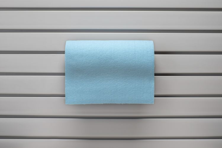 A blue towel is hanging on a rack on a wall.