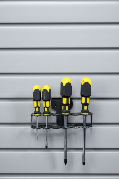 Four screwdrivers are hanging on a rack on a wall.