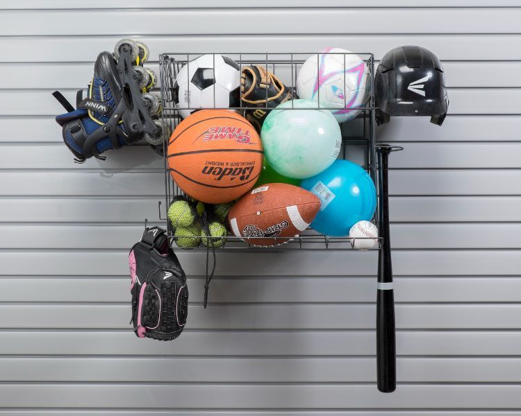 A bunch of sports balls are hanging on a wall.