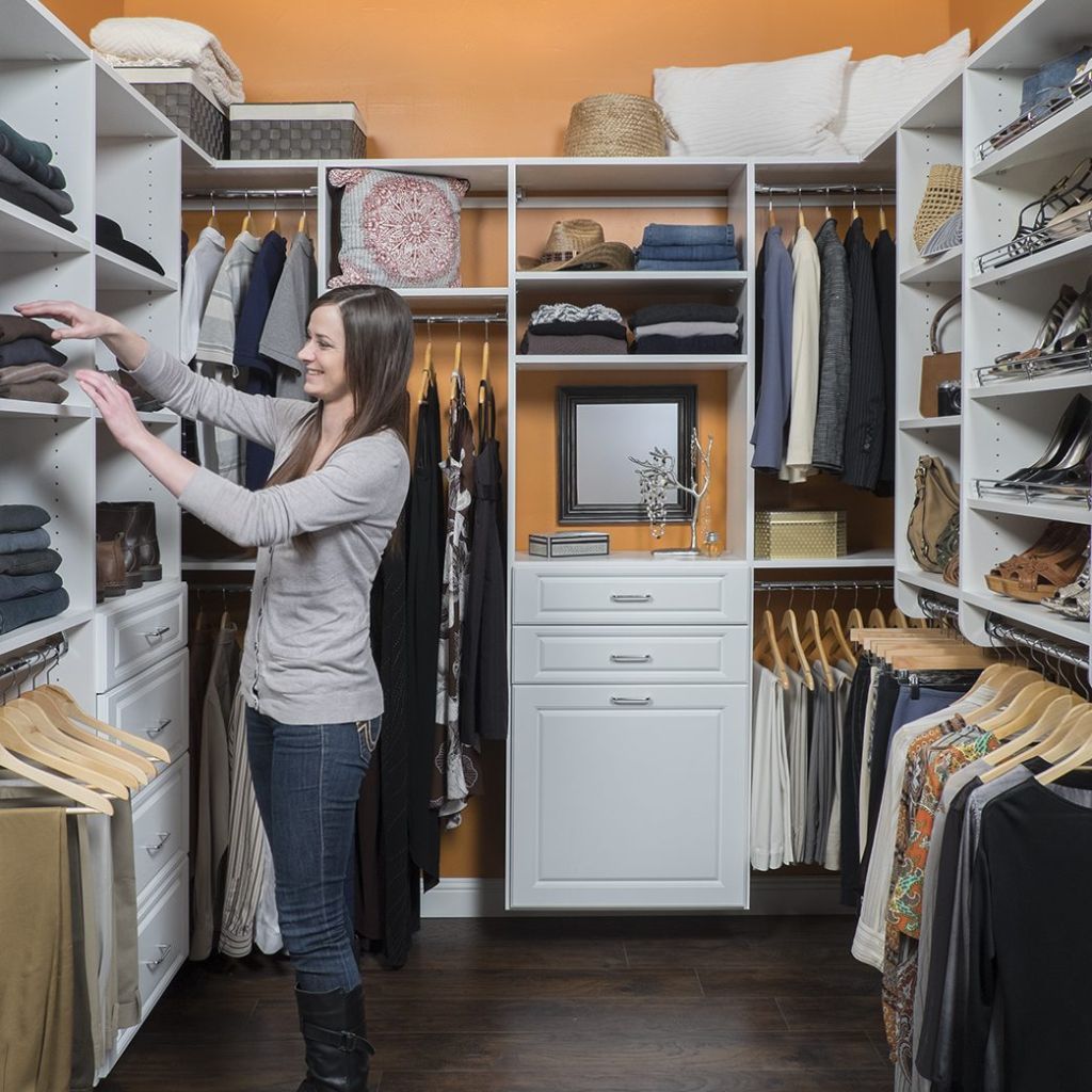 A woman is standing in a walk in closet looking at clothes