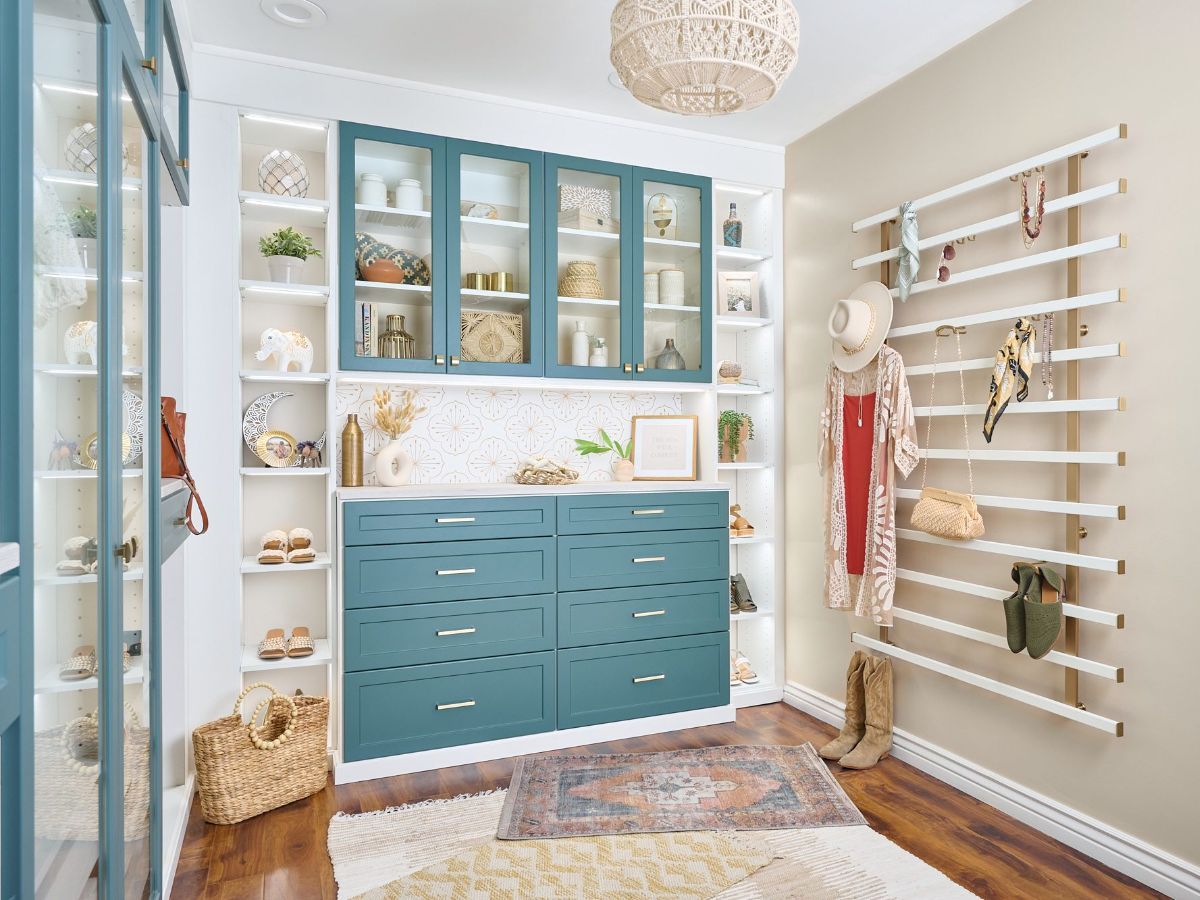 A walk in closet with blue cabinets and white shelves.