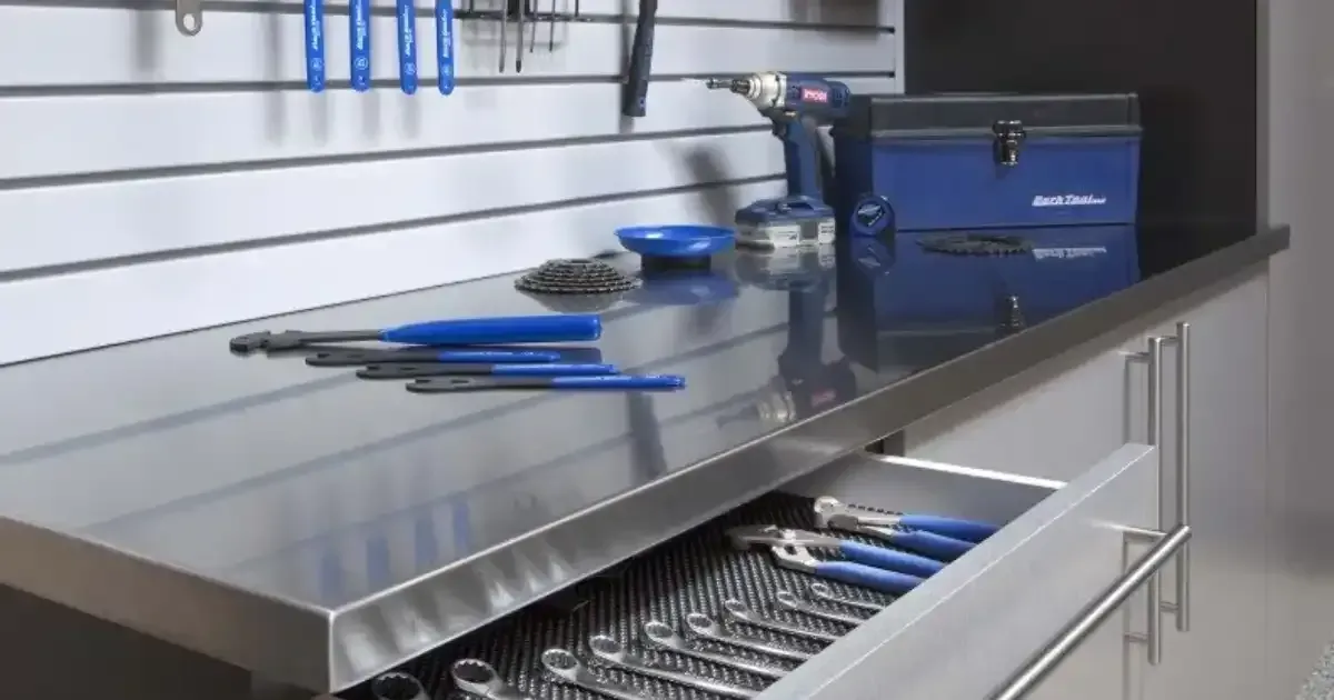 A stainless steel workbench with a drawer filled with tools.