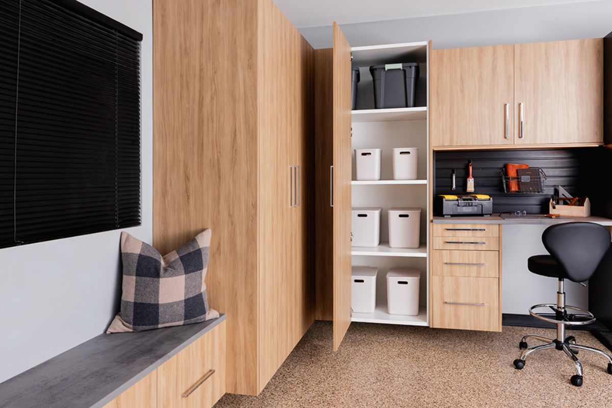A garage system with wooden cabinets , a bench , a desk and a chair.