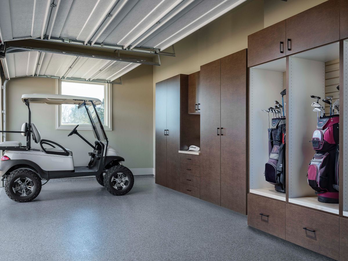 A golf cart is parked in a garage with lots of cabinets.