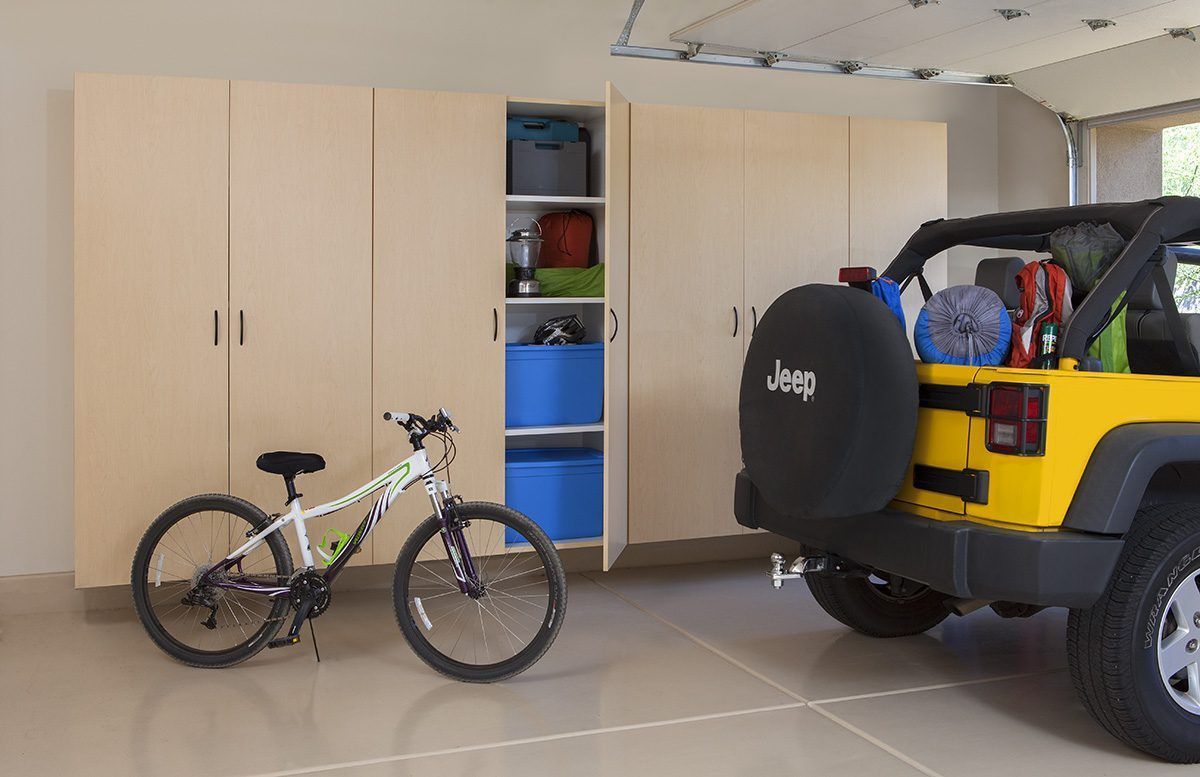 A jeep is parked in a garage next to a bike.