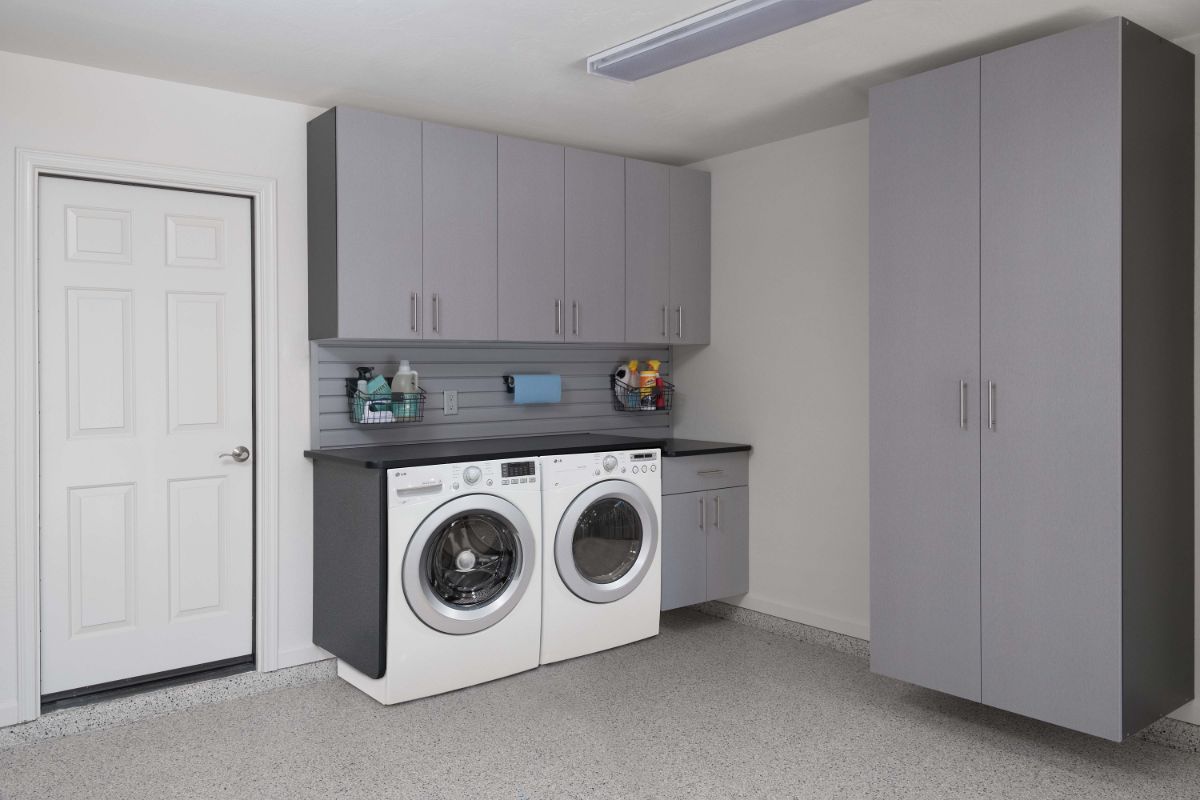 A laundry room with a washer and dryer and gray cabinets.