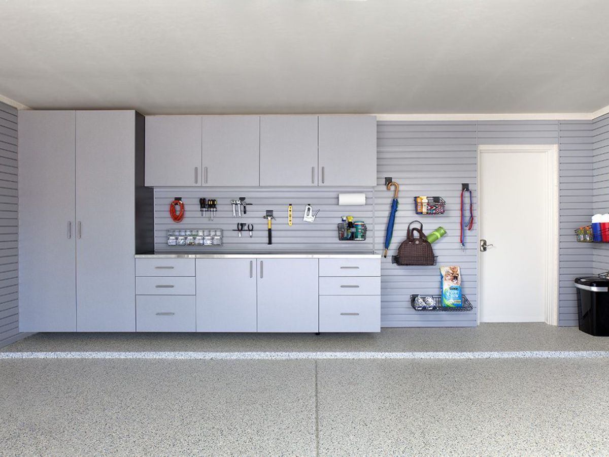 A garage with white cabinets , drawers , and a sink.