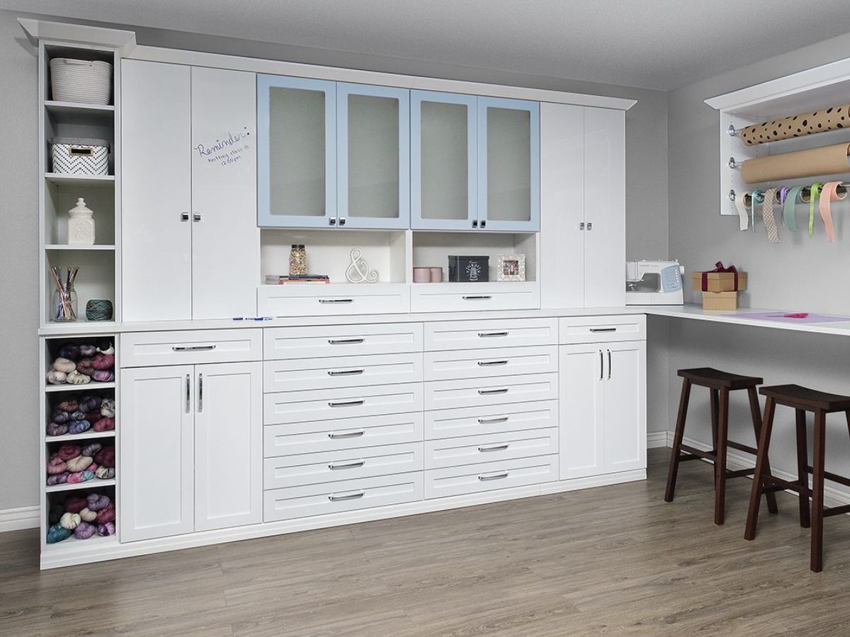 A Craft room with a lot of white cabinets and drawers