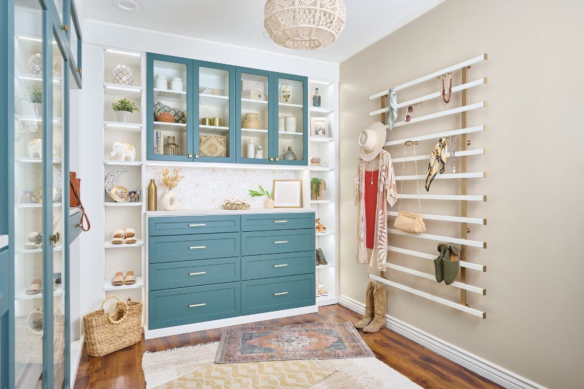 A walk in closet with blue cabinets and white shelves.
