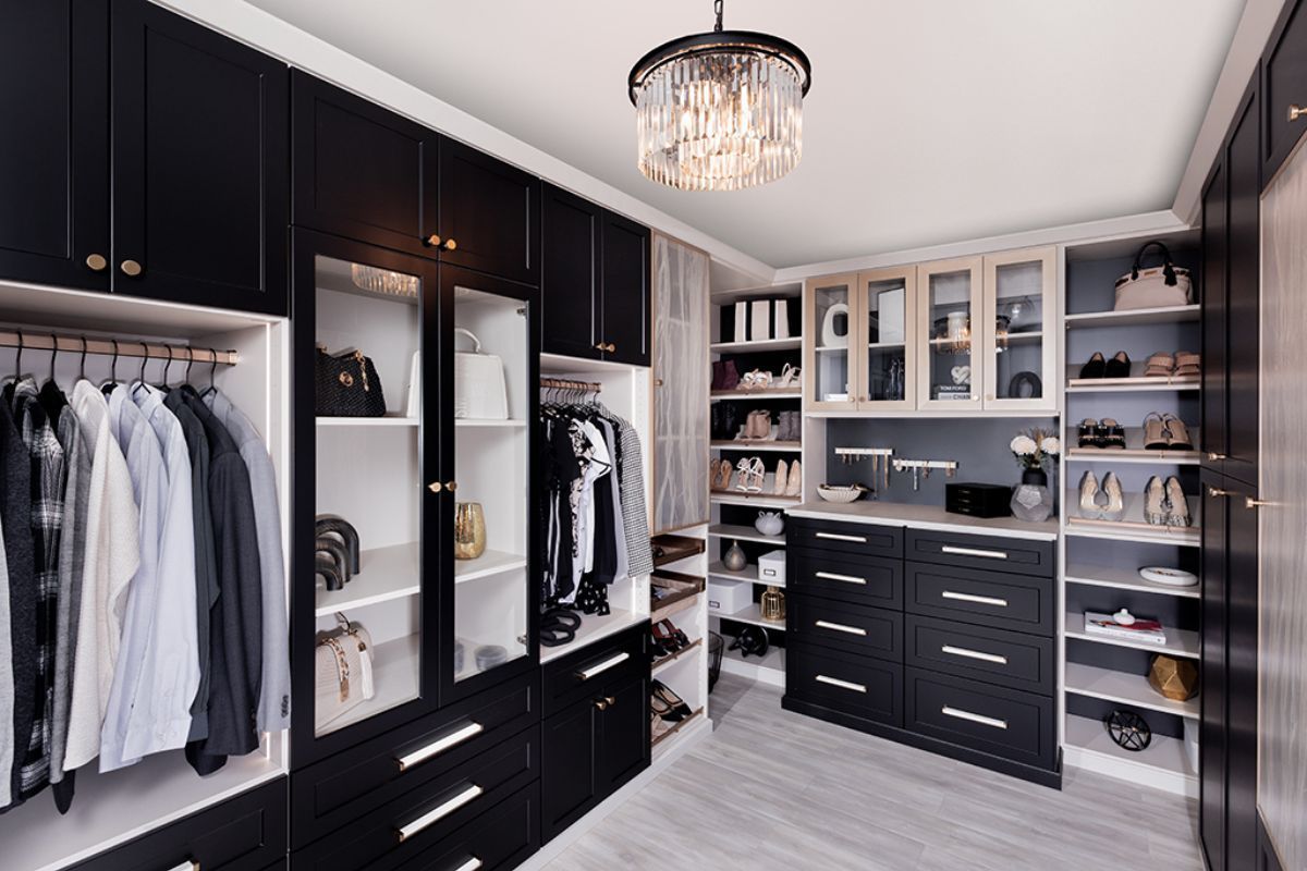 A walk in closet with black cabinets and white shelves