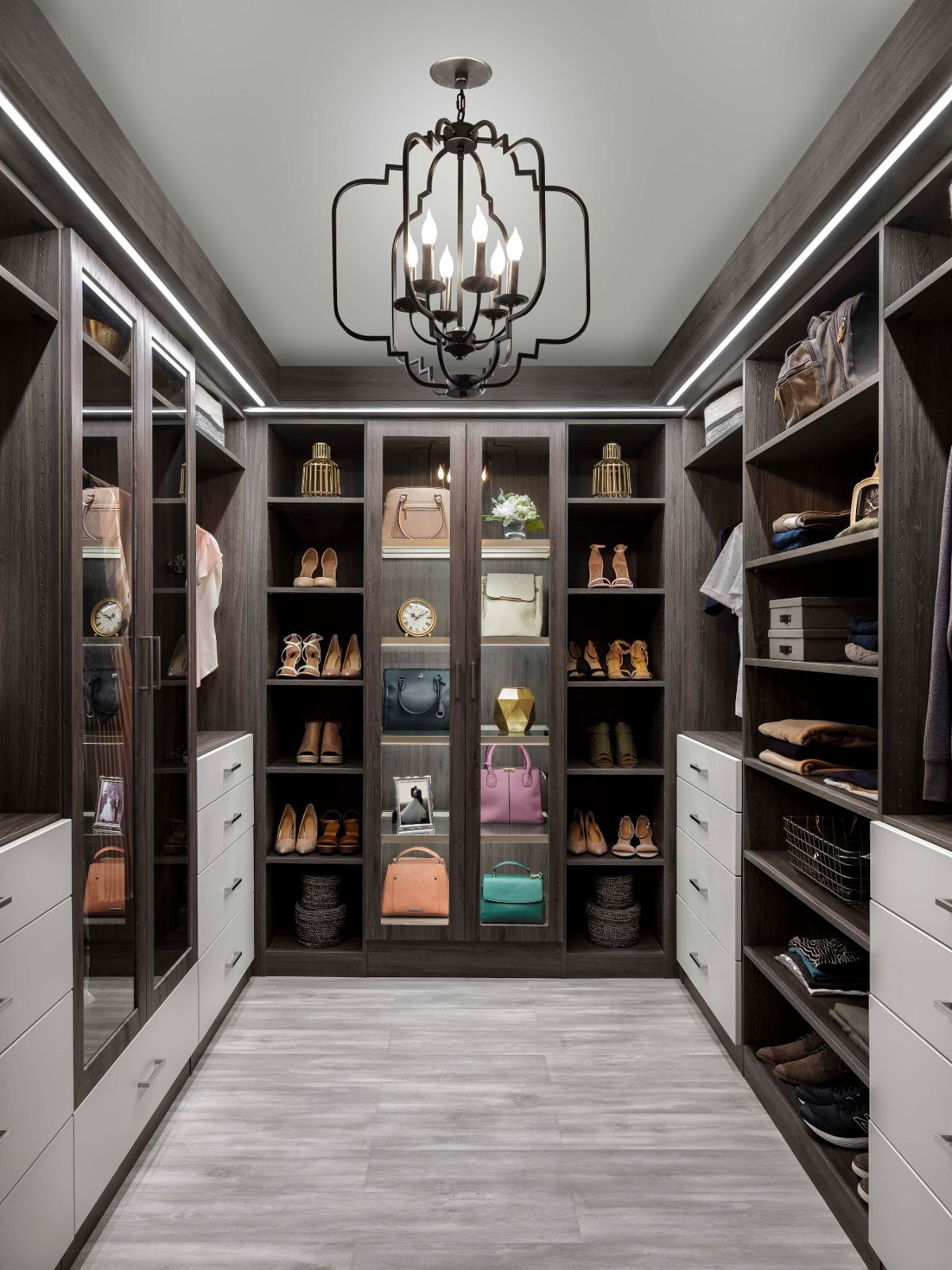 A walk in closet with lots of shelves and a chandelier.