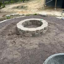 Stone fire pit in a dirt clearing.