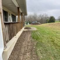 Exterior of a house with a porch and a dirt path through a grassy area. Cloudy sky.