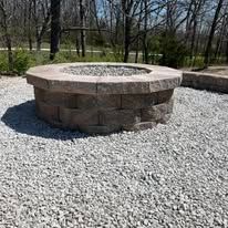 A stone fire pit on a gravel patio.