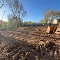 A freshly graded lot with dirt and a bulldozer, ready for construction, under a blue sky.