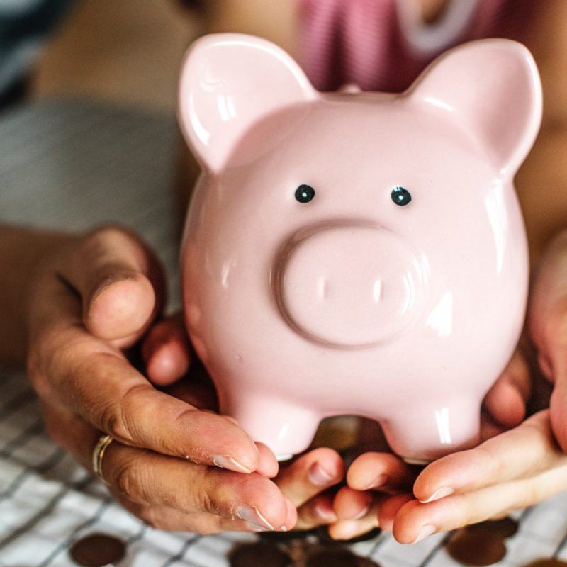 Pink piggy bank held in open hands.