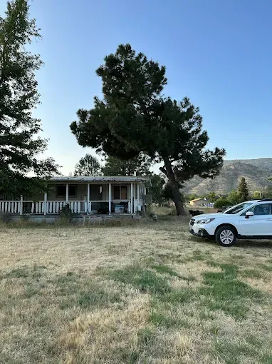 A white suv is parked in front of a house with a porch.
