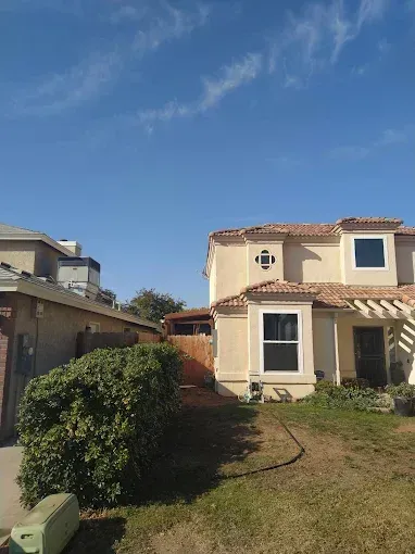A house with a pergola and a hose in front of it.