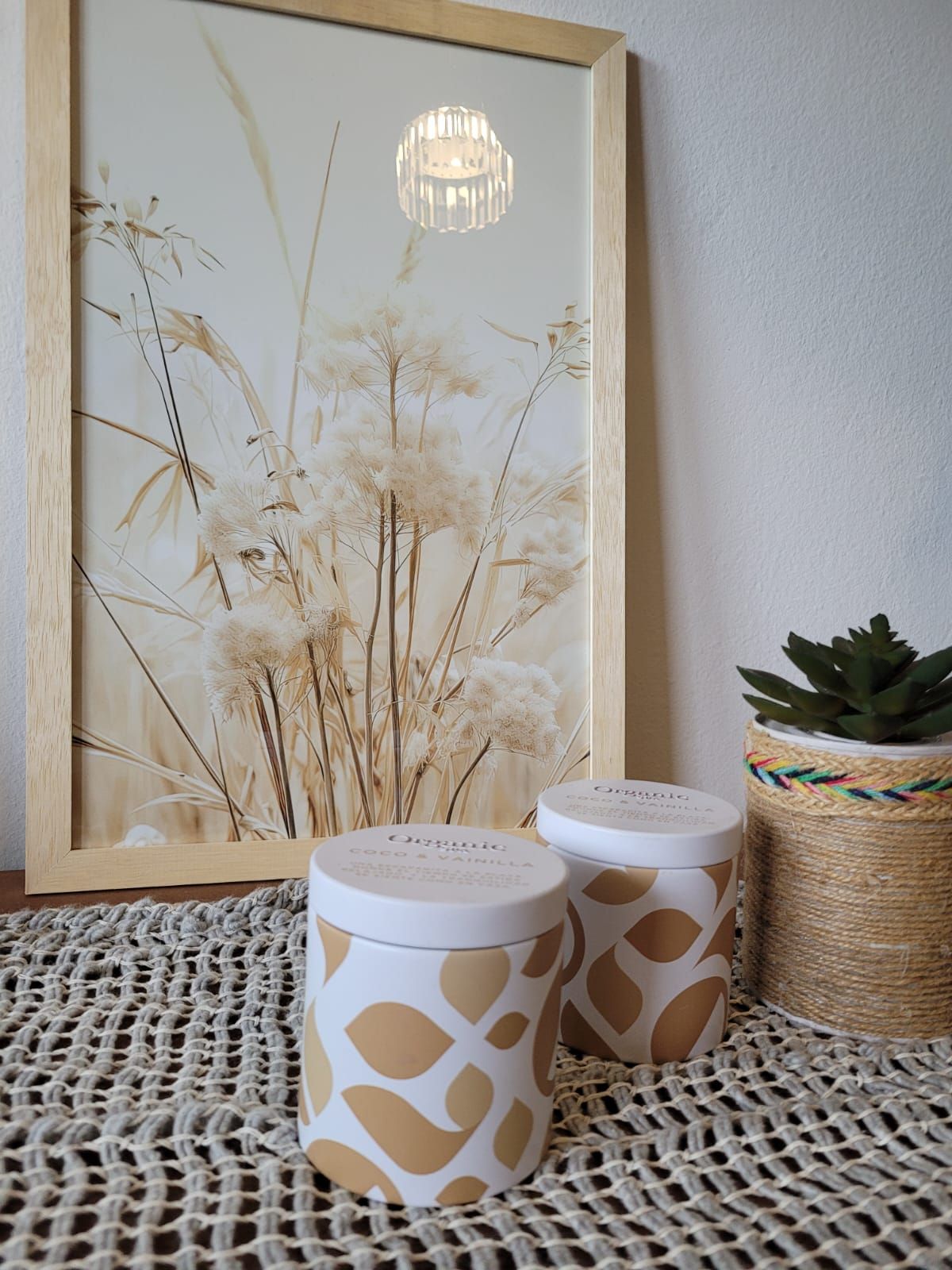Pared minimalista de color beige en la sala de estar con tres láminas botánicas enmarcadas sobre un sofá color crema.