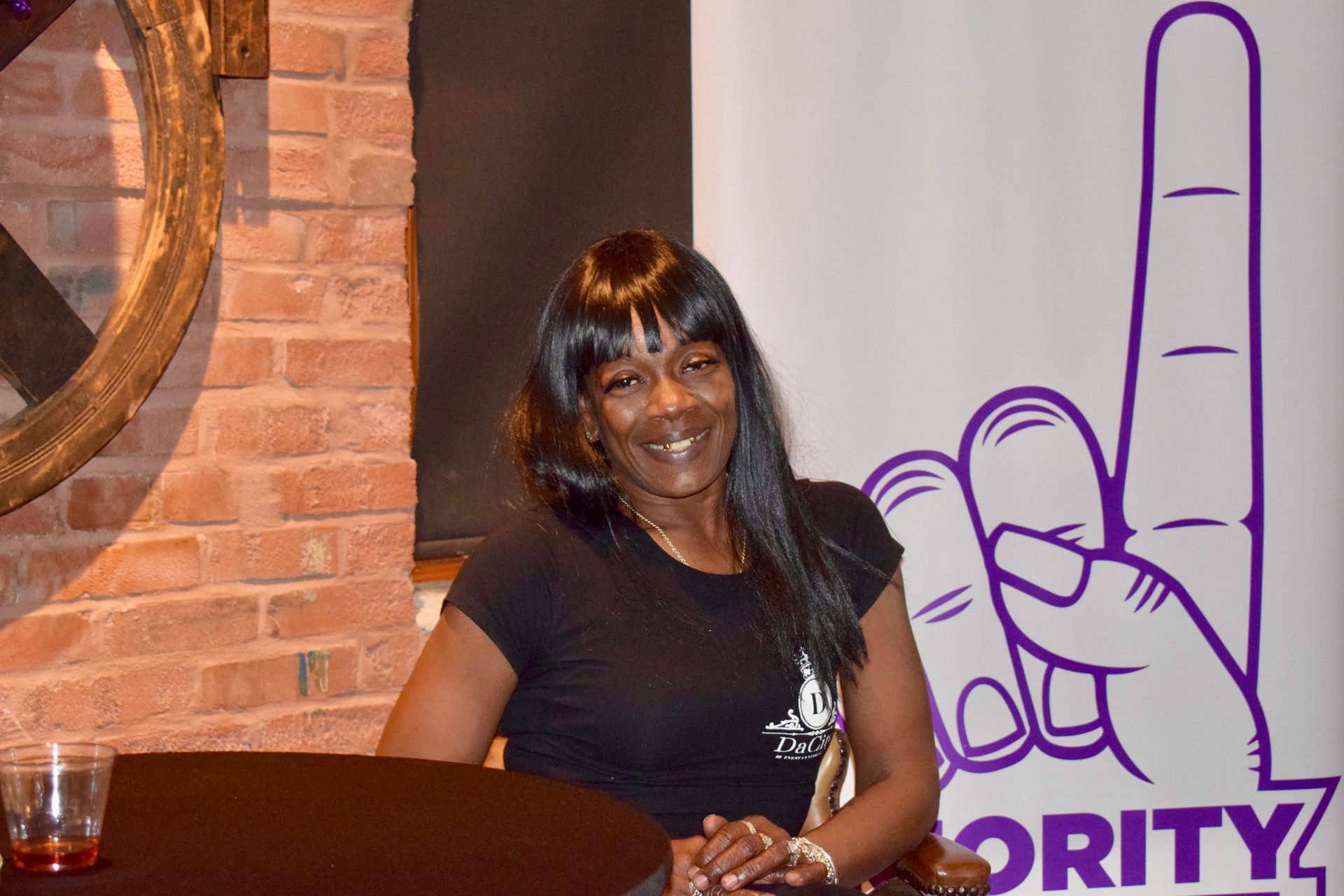 A Woman Is Sitting at A Table in Front of A Sign — Saint Louis, MO — Priority One Healthcare Services