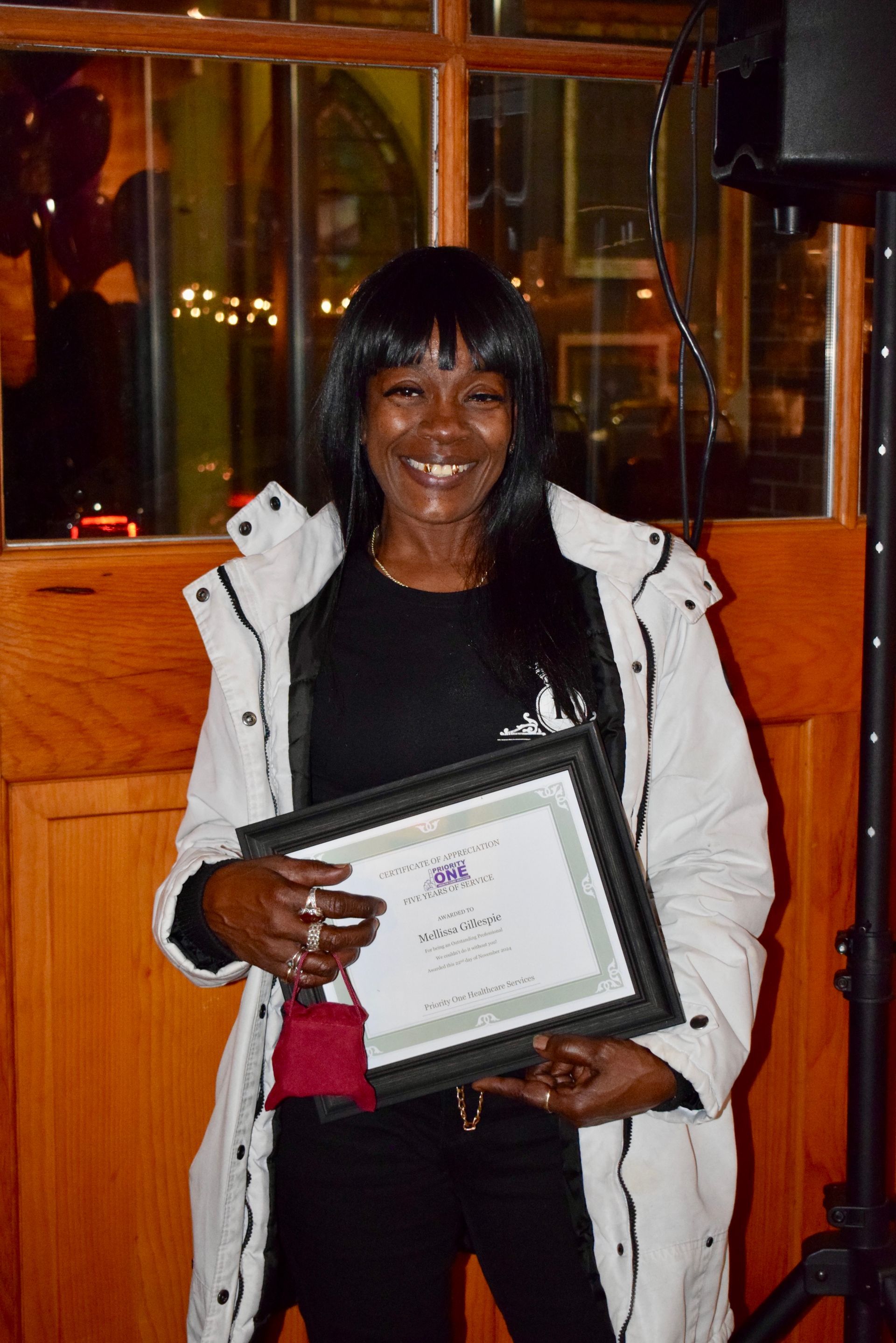 A Woman in A White Coat Is Holding a Certificate — Saint Louis, MO — Priority One Healthcare Services