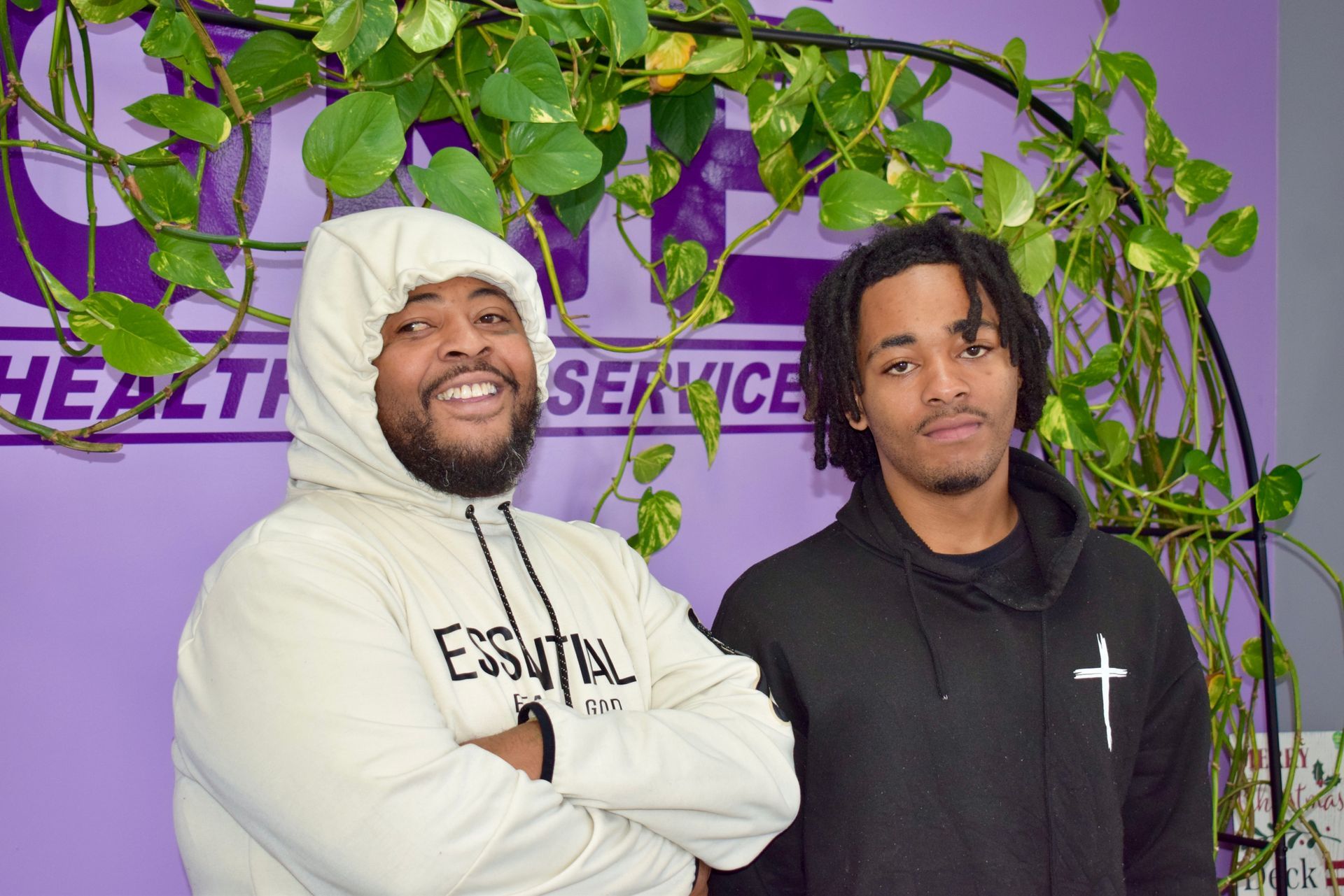 Two Men Are Standing Next to Each Other with Their Arms Crossed in Front of A Purple Background.