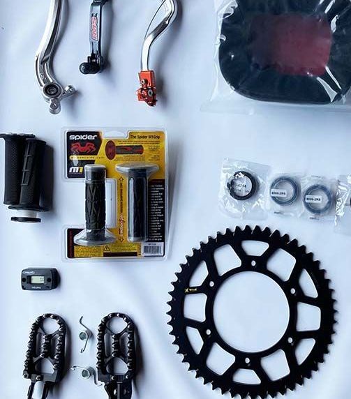 A variety of motorcycle parts are laid out on a white surface