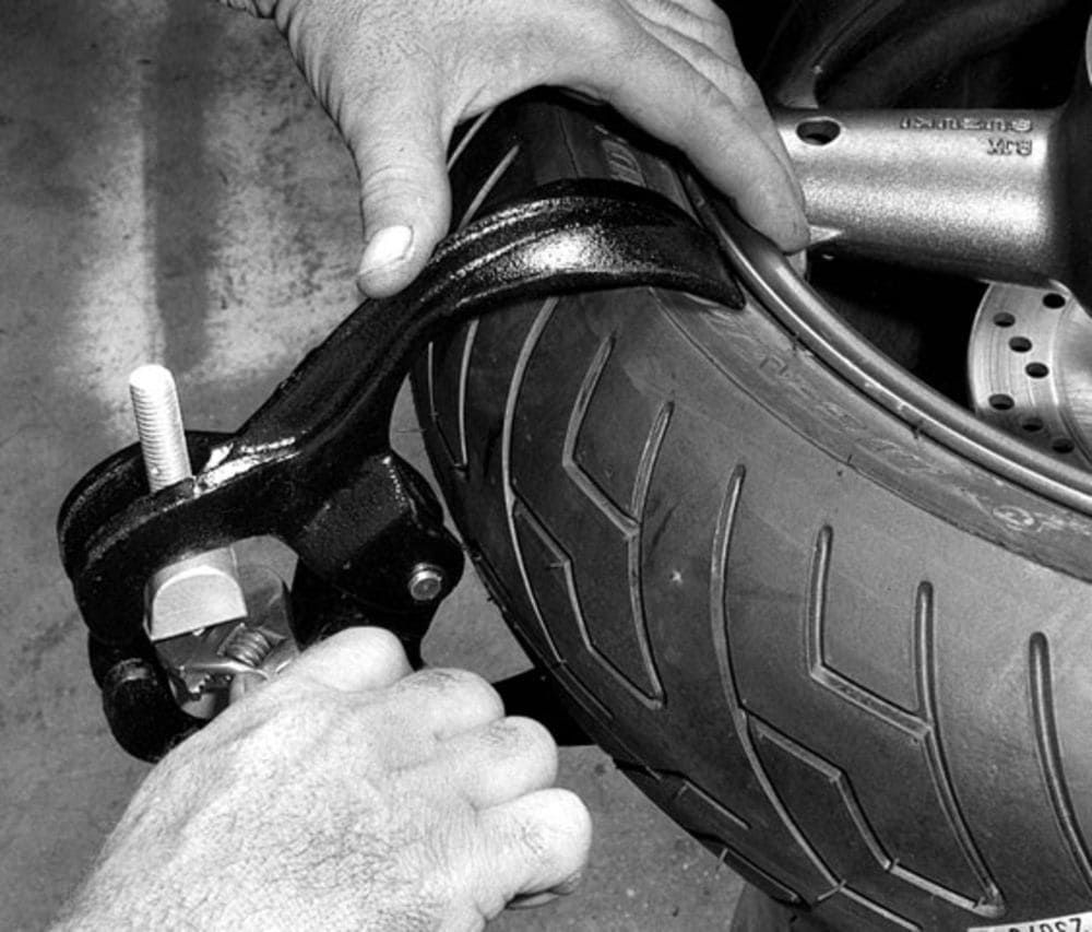 A black and white photo of a person working on a tire