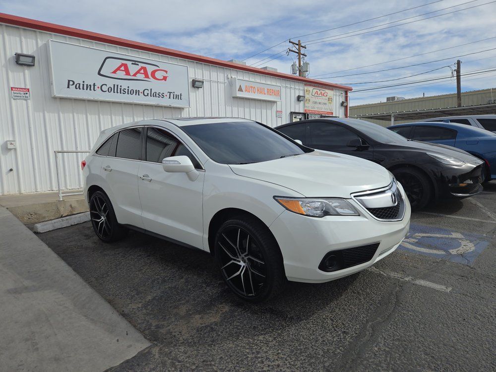 White Acura RDX SUV parked outside a building with a “Paint, Column, Glass Tint” sign.