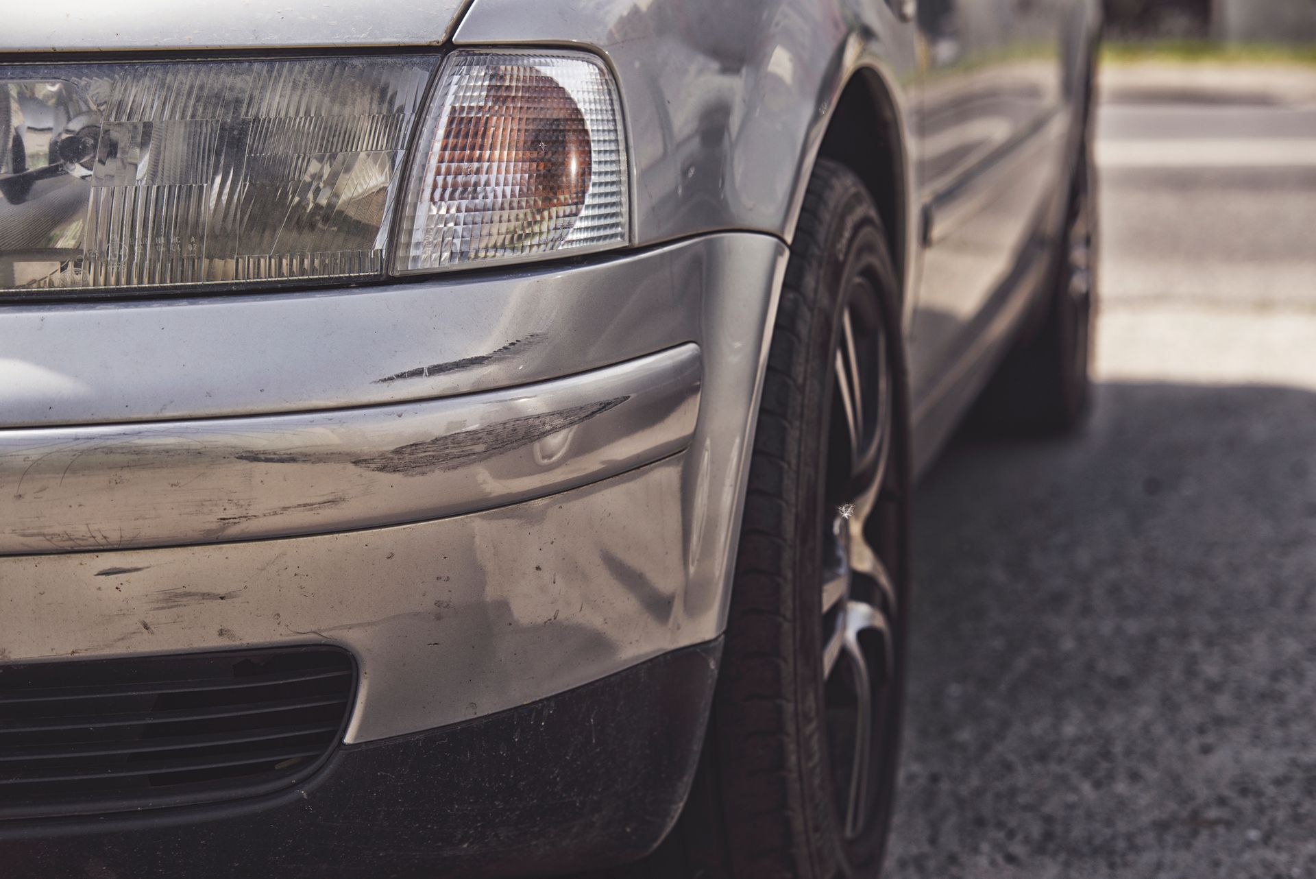 the front of a car with scratches on the bumper.
