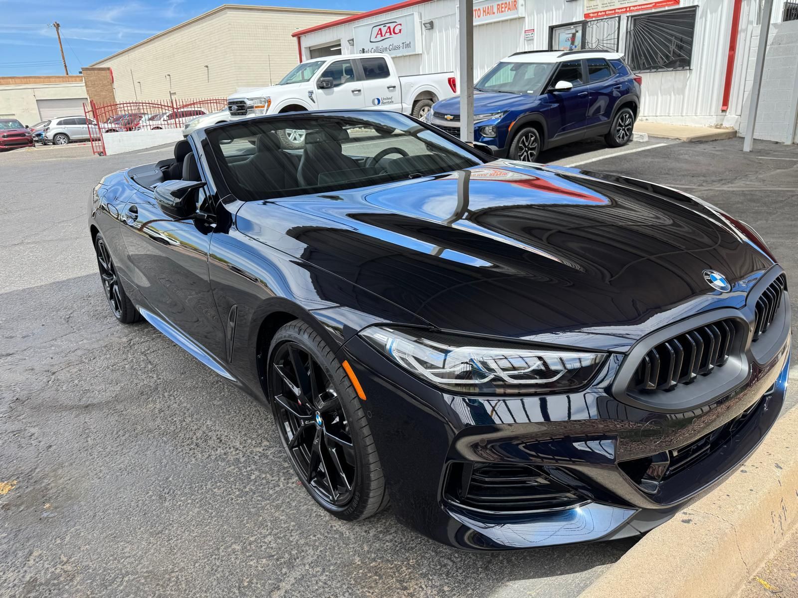 Black BMW convertible parked in front of a building on a sunny day.
