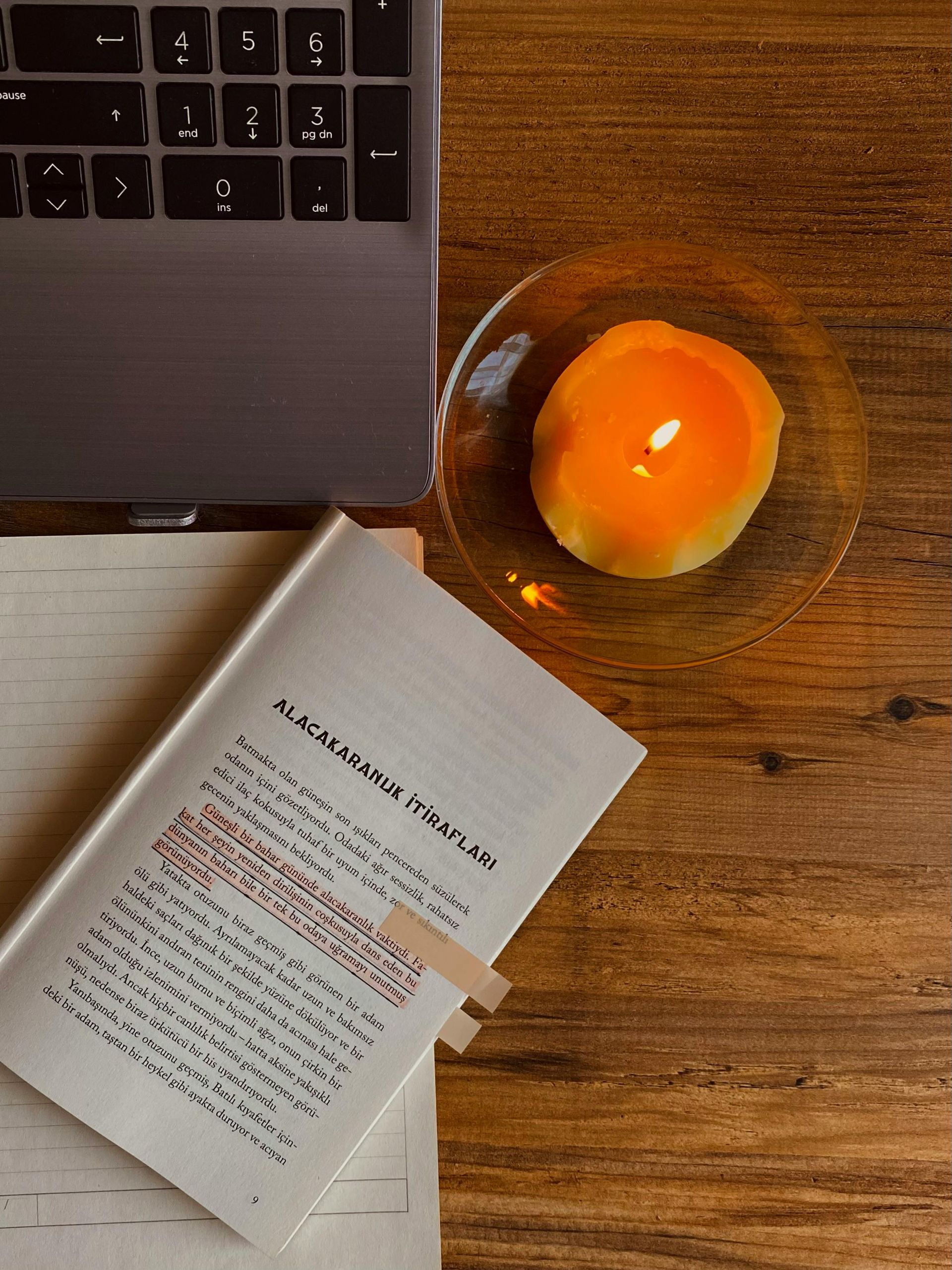 A person holds a phone displaying a calendar app at a desk with a clock, a plant, and a laptop.
