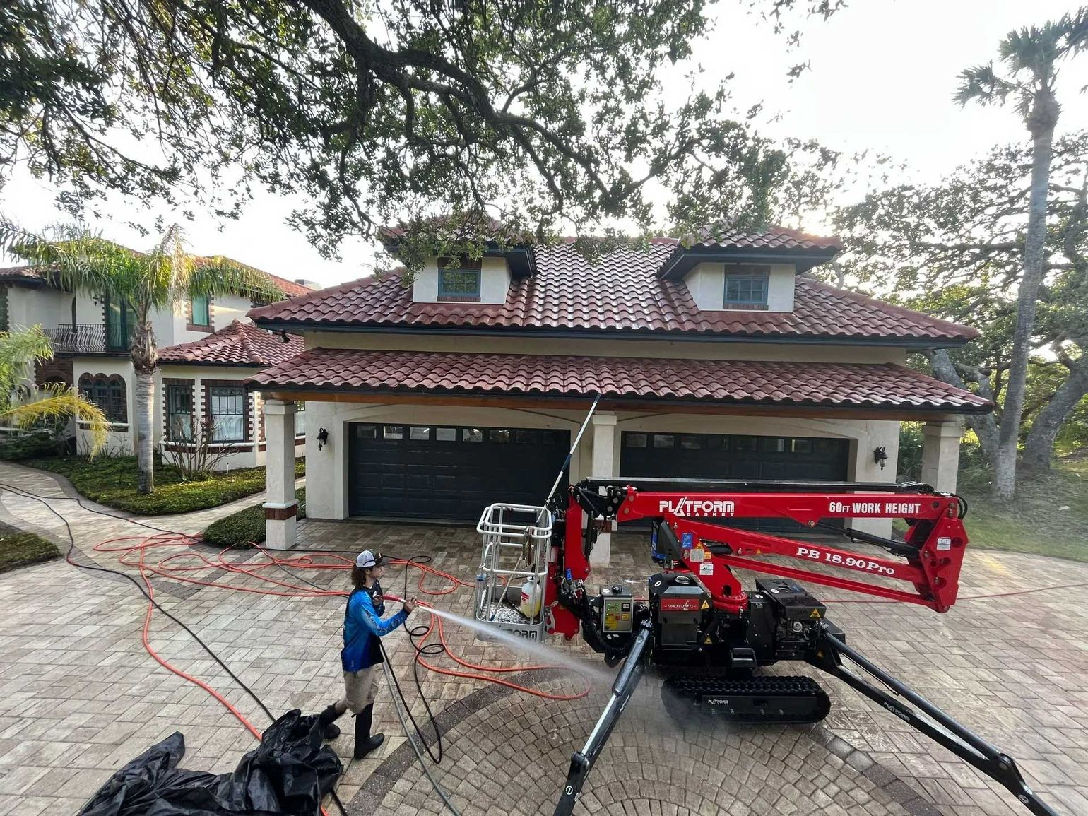 A Man is Cleaning the Roof of a House with a Platform Lift