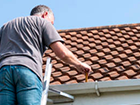 a man is standing on a ladder on top of a roof .