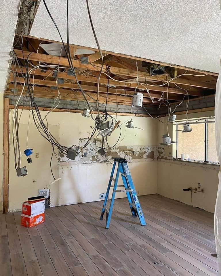 A ladder is sitting in a room with a lot of wires hanging from the ceiling.