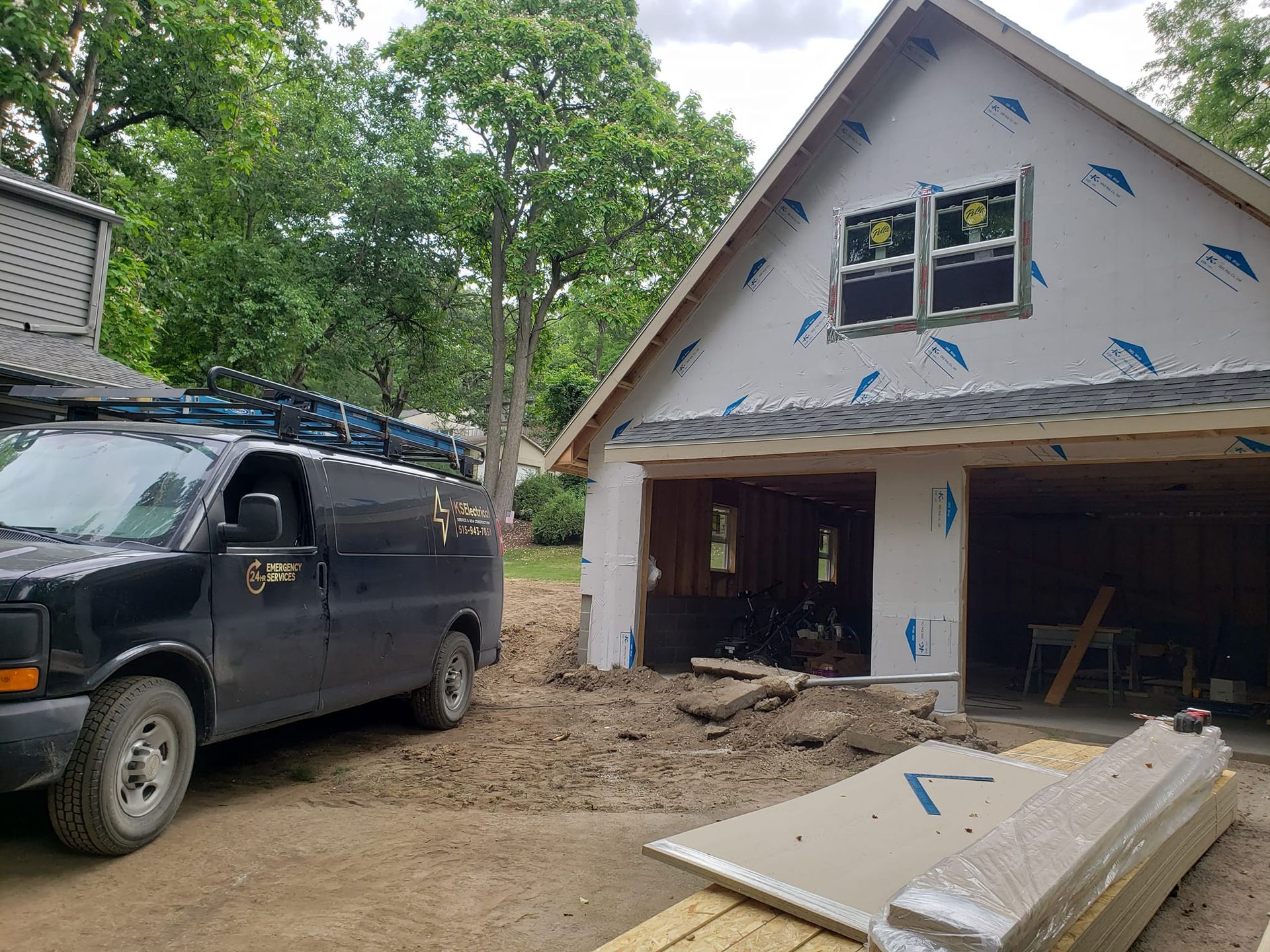 A black van is parked in front of a garage under construction.