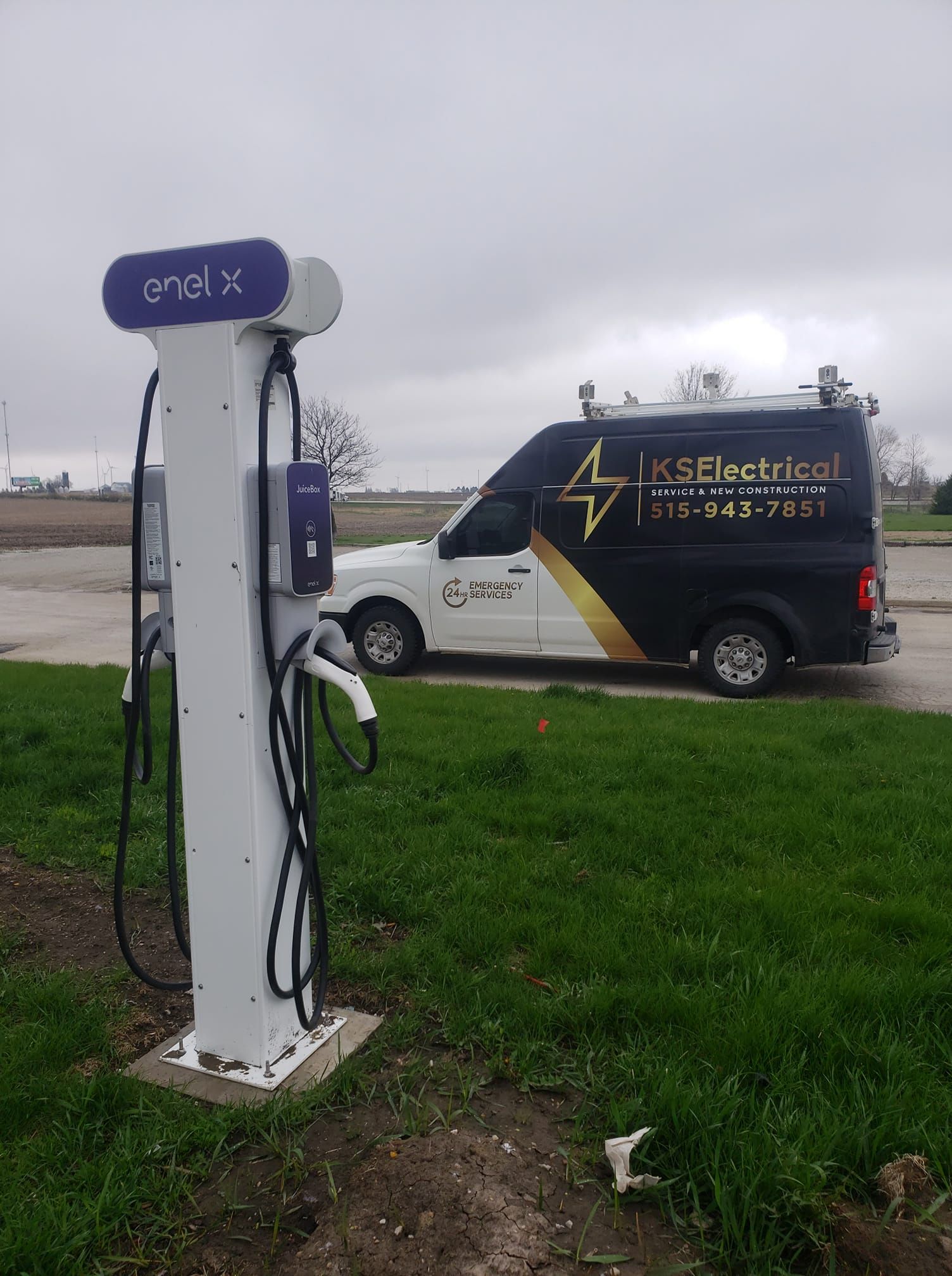 A white van is parked next to a charging station.