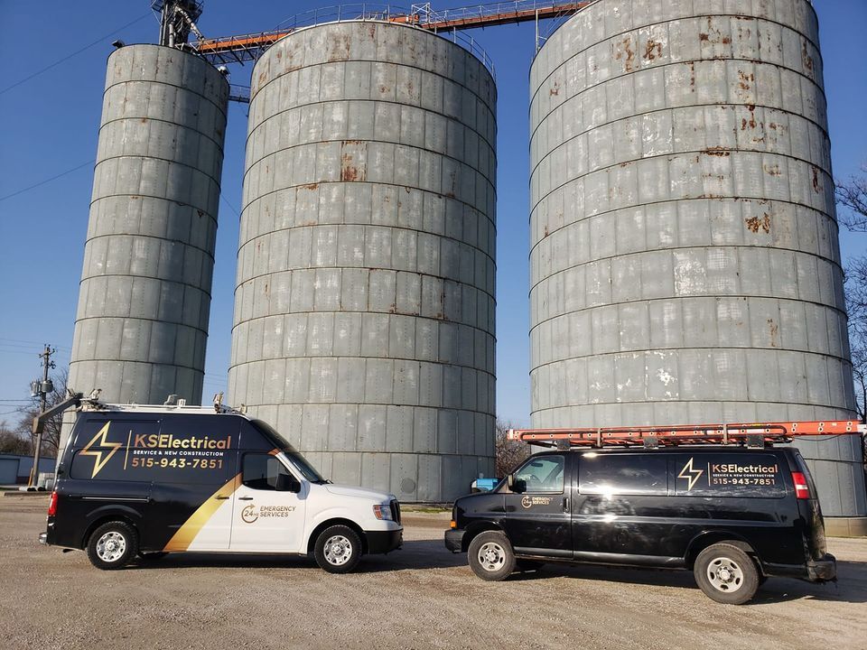 Two vans are parked in front of a row of silos