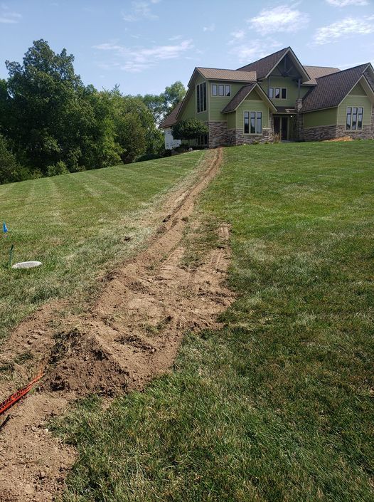 A dirt road leading to a large house on a hill.