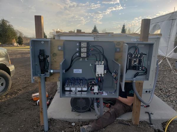 A man is laying on the ground working on a electrical box.