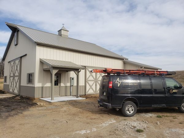 A black van is parked in front of a barn
