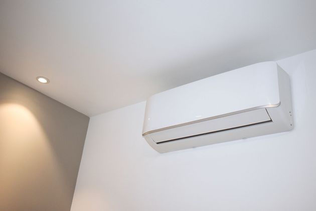 A white air conditioner is hanging on a white wall in a room.