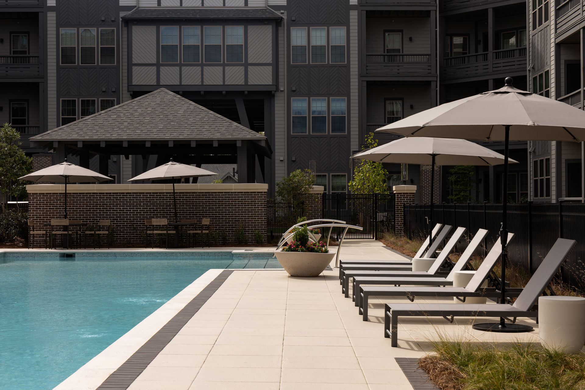 Swimming pool with lounge chairs and umbrellas at an apartment complex.