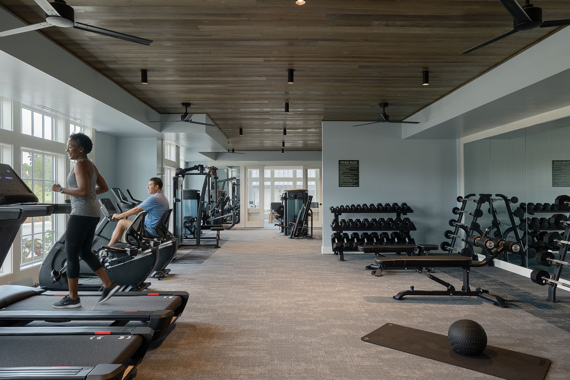 Gym interior with exercise equipment and two people working out.