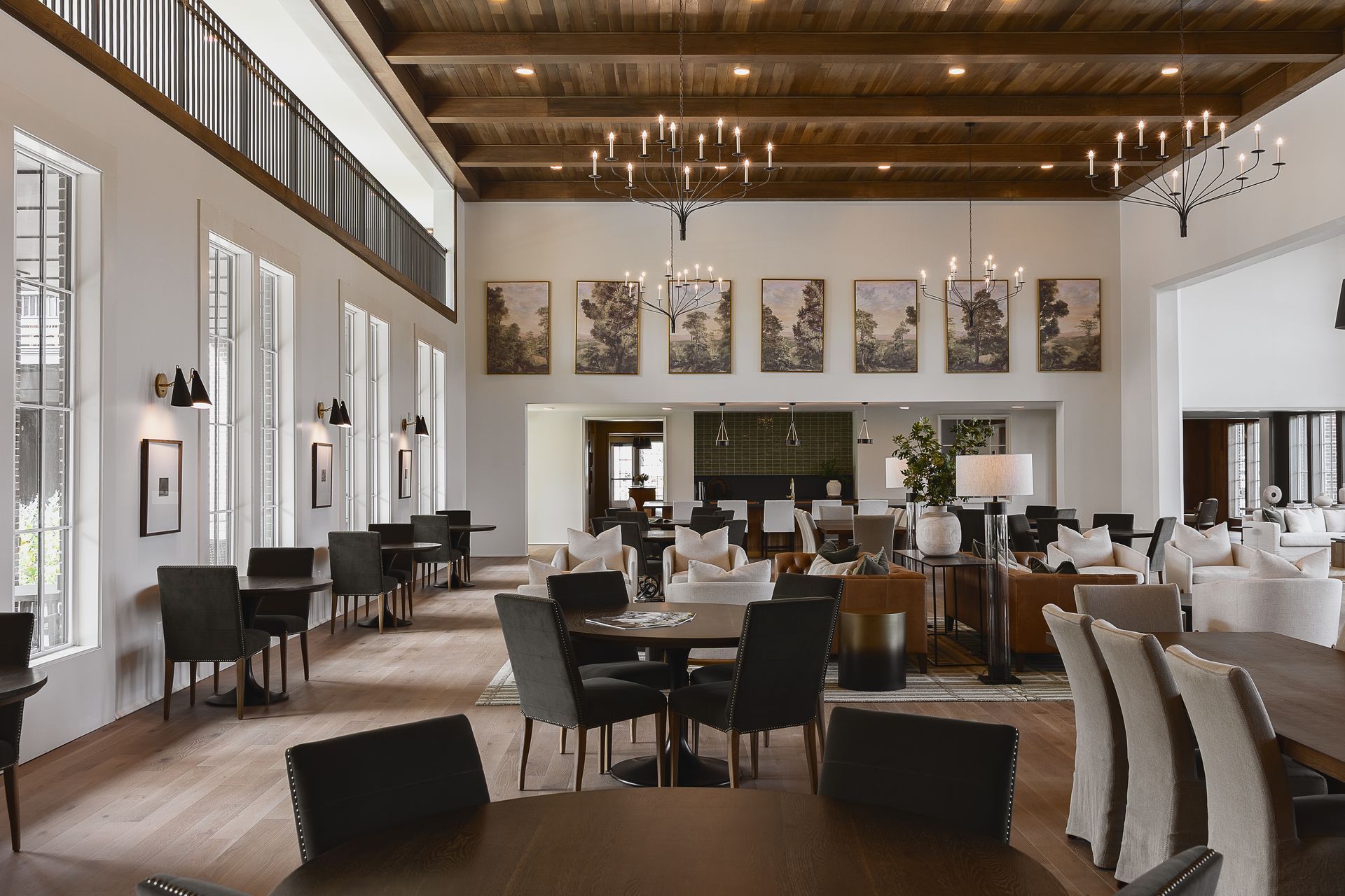 Elegant interior with tables, chairs, and artwork; wood beams and chandeliers.