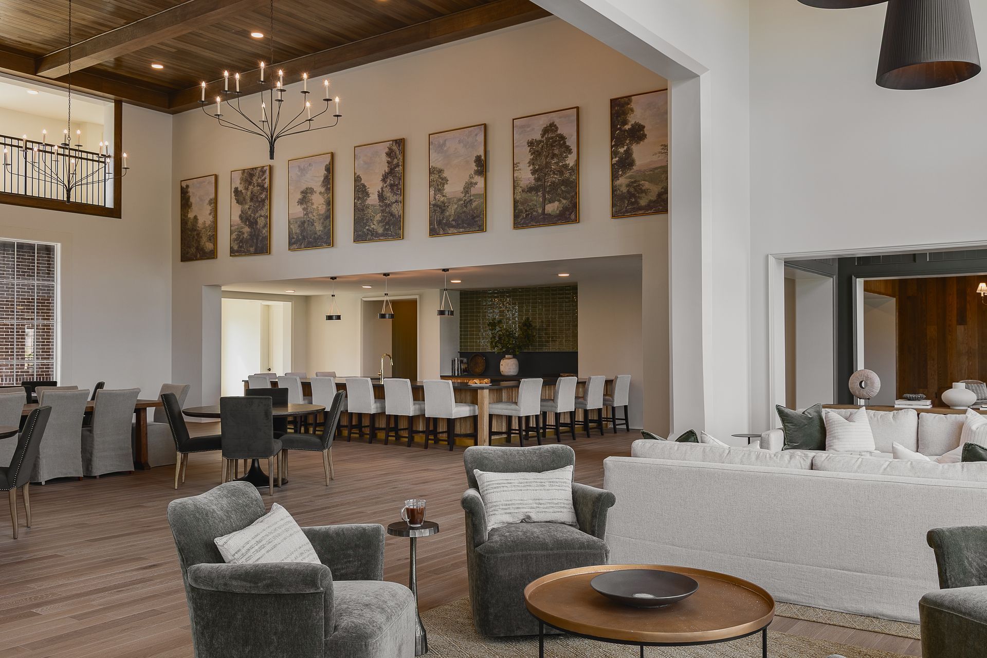 Spacious modern lounge with couches, armchairs, and dining tables, neutral tones, large windows, and artwork.